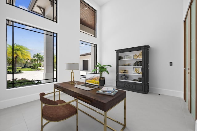 office area featuring a towering ceiling and light tile patterned flooring