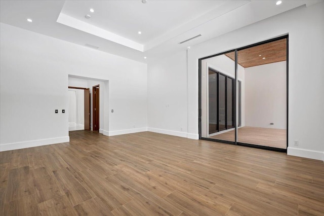 unfurnished room with light wood-type flooring and a raised ceiling