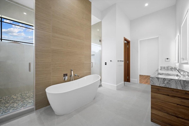 bathroom with tile walls, tile patterned flooring, separate shower and tub, and vanity