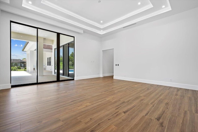 empty room with wood-type flooring and a tray ceiling