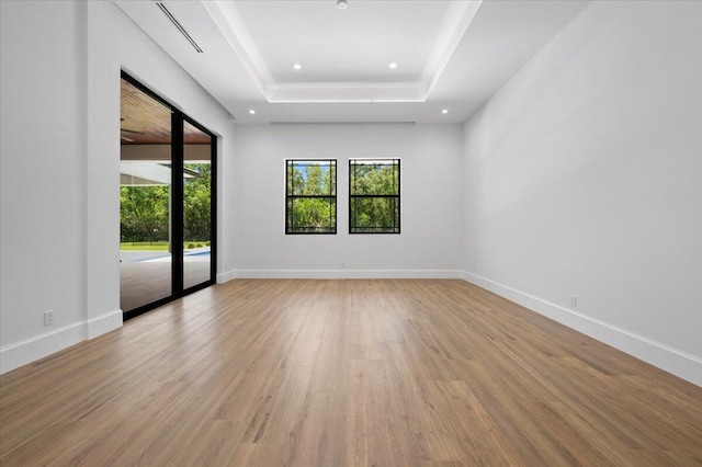 spare room with light wood-type flooring and a raised ceiling