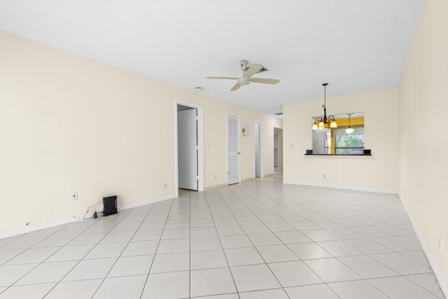 tiled empty room featuring ceiling fan with notable chandelier