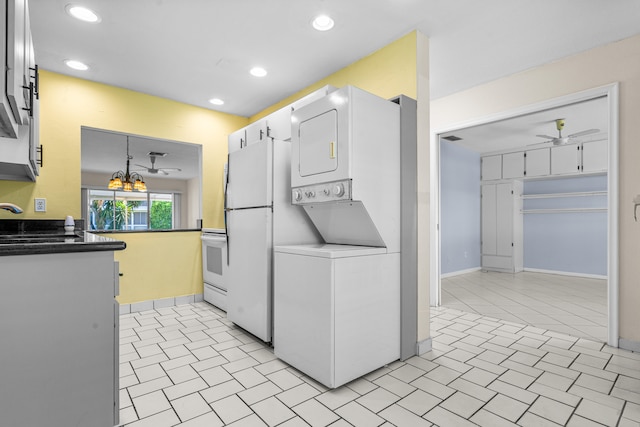 kitchen with ceiling fan, sink, white cabinets, stacked washer and dryer, and hanging light fixtures