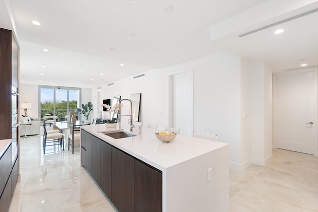 kitchen featuring a large island, oven, dark brown cabinets, and sink