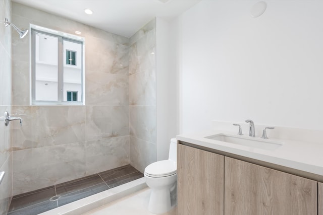 bathroom with vanity, toilet, and a tile shower