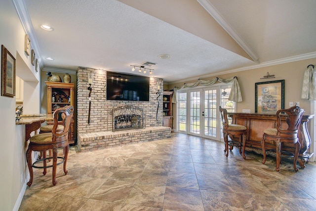 living room with french doors, crown molding, indoor bar, a brick fireplace, and a textured ceiling