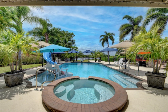 view of pool with an in ground hot tub, a patio, and a water slide