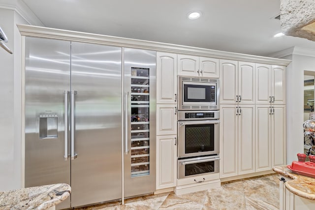 kitchen with white cabinets, built in appliances, light stone counters, and ornamental molding