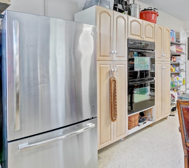 kitchen with black double oven and stainless steel refrigerator