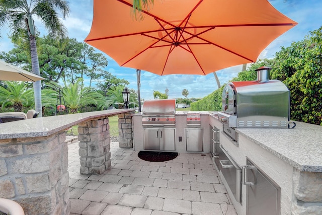 view of patio / terrace featuring exterior bar, area for grilling, and a grill