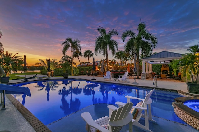 pool at dusk with a gazebo, an in ground hot tub, and a patio