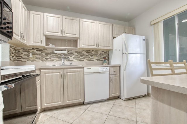 kitchen with tasteful backsplash, sink, light tile patterned floors, and white appliances