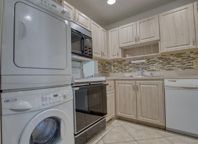 kitchen with black appliances, decorative backsplash, light tile patterned floors, and stacked washer and dryer