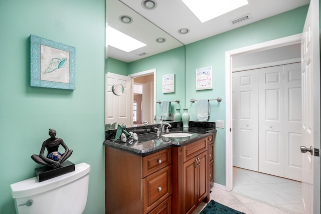 bathroom featuring tile patterned floors, vanity, toilet, and a skylight