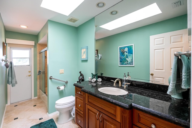 full bathroom with a skylight, bath / shower combo with glass door, vanity, tile patterned flooring, and toilet