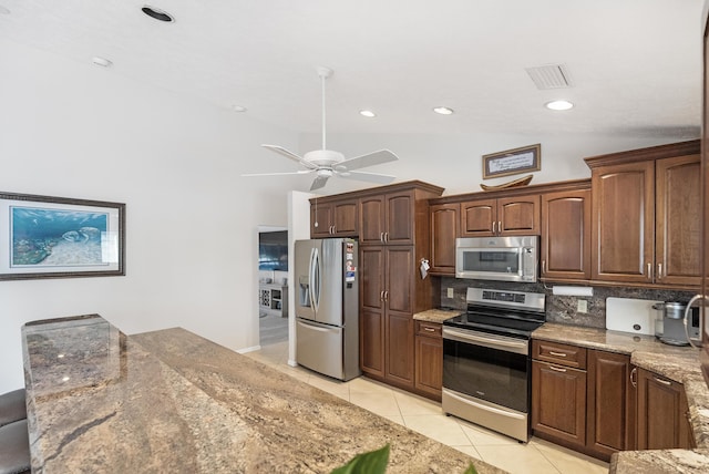 kitchen with vaulted ceiling, ceiling fan, tasteful backsplash, light tile patterned flooring, and stainless steel appliances