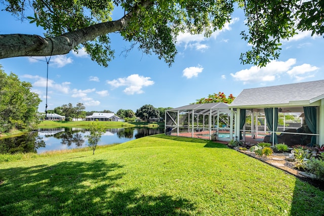 view of yard with glass enclosure, a swimming pool, and a water view