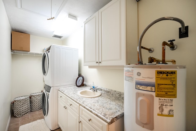 laundry area with sink, cabinets, electric water heater, light tile patterned floors, and stacked washer and clothes dryer