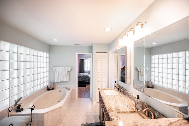 bathroom featuring vanity, tiled bath, tile patterned floors, and a wealth of natural light