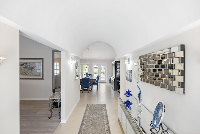 corridor with light tile patterned floors and lofted ceiling