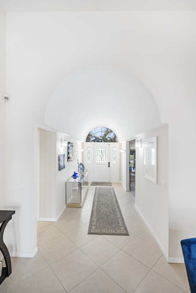 foyer entrance with light tile patterned floors and vaulted ceiling