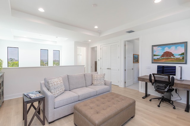 living room with a tray ceiling and light wood-type flooring