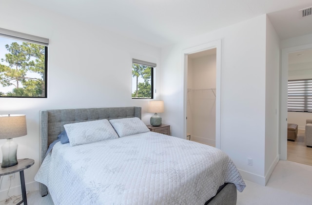 bedroom featuring light colored carpet, a spacious closet, and a closet