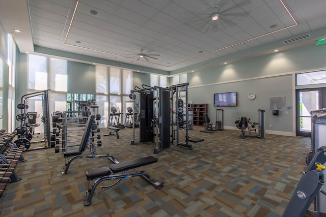 workout area with carpet flooring, a wealth of natural light, ceiling fan, and a high ceiling