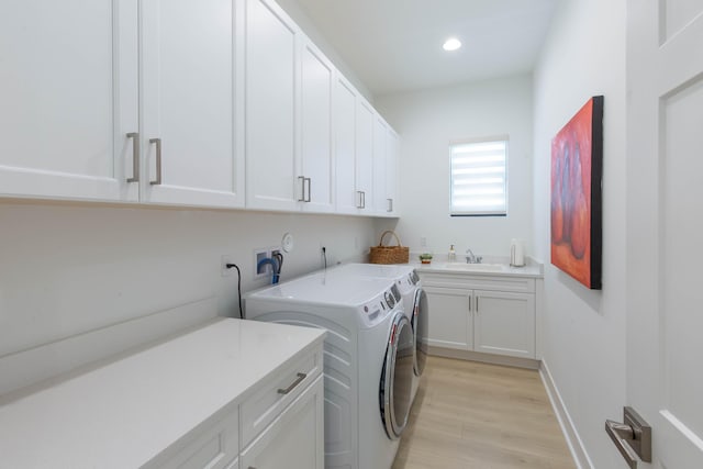 laundry room with light hardwood / wood-style floors, cabinets, independent washer and dryer, and sink