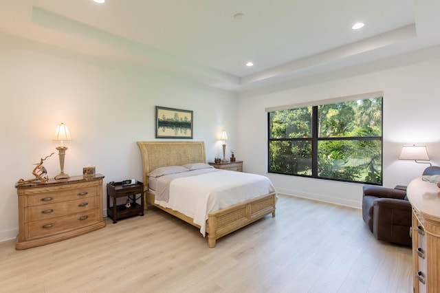 bedroom featuring a raised ceiling and light hardwood / wood-style flooring