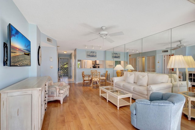 living room with rail lighting, a textured ceiling, ceiling fan, and light hardwood / wood-style flooring