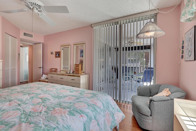 bedroom featuring access to exterior, ceiling fan, light hardwood / wood-style floors, and a textured ceiling