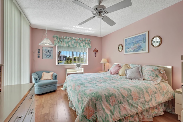 bedroom featuring ceiling fan, light wood-type flooring, and a textured ceiling