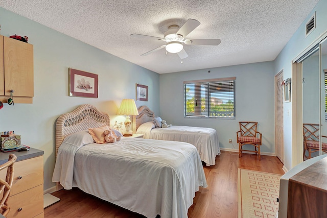 bedroom featuring ceiling fan, a textured ceiling, and light hardwood / wood-style flooring