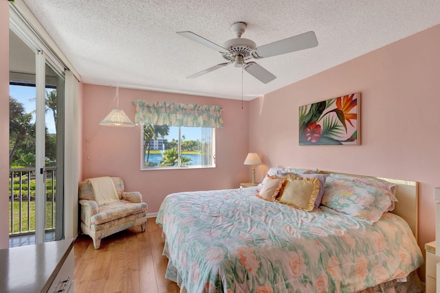 bedroom featuring access to exterior, light hardwood / wood-style floors, a textured ceiling, and ceiling fan