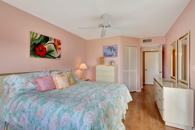 bedroom with ceiling fan, light hardwood / wood-style floors, and a textured ceiling