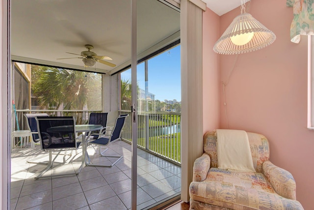 sunroom / solarium featuring a water view and ceiling fan