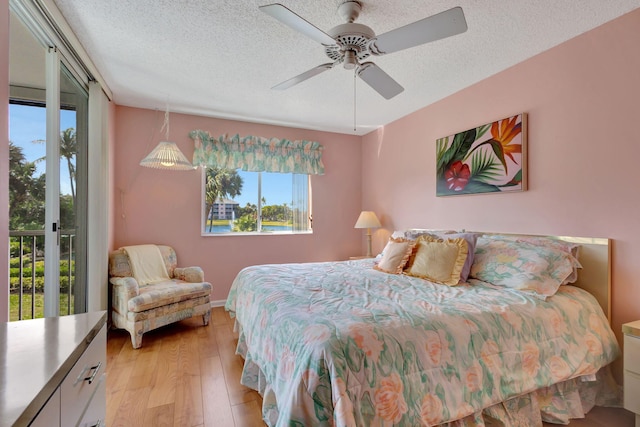 bedroom featuring access to exterior, light hardwood / wood-style flooring, a textured ceiling, and ceiling fan