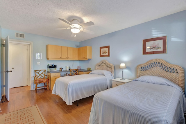 bedroom with ceiling fan, a textured ceiling, and light wood-type flooring