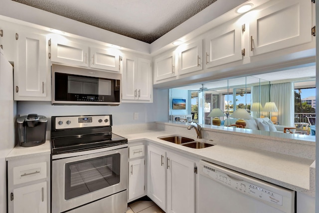 kitchen with light tile patterned floors, stainless steel appliances, sink, and white cabinets