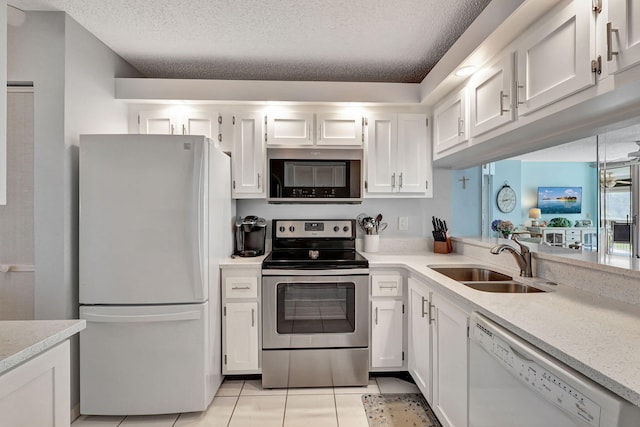 kitchen with a textured ceiling, light tile patterned flooring, sink, and appliances with stainless steel finishes