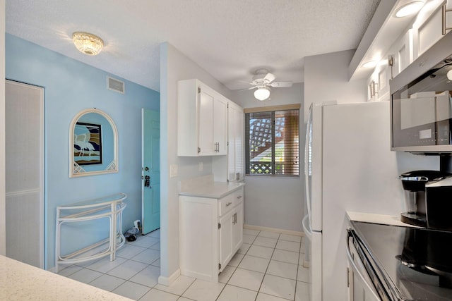 kitchen featuring light tile patterned flooring, a textured ceiling, white cabinets, and ceiling fan