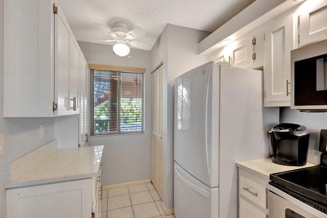 kitchen with stainless steel appliances, white cabinetry, light tile patterned floors, and ceiling fan