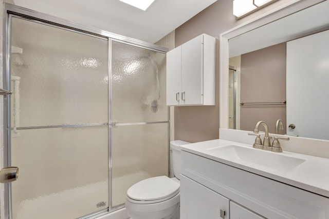 bathroom with vanity, a shower with shower door, and toilet