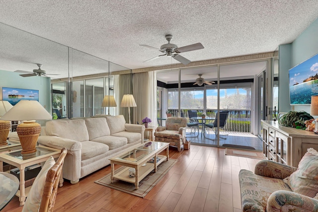 living room with ceiling fan, wood-type flooring, and a textured ceiling