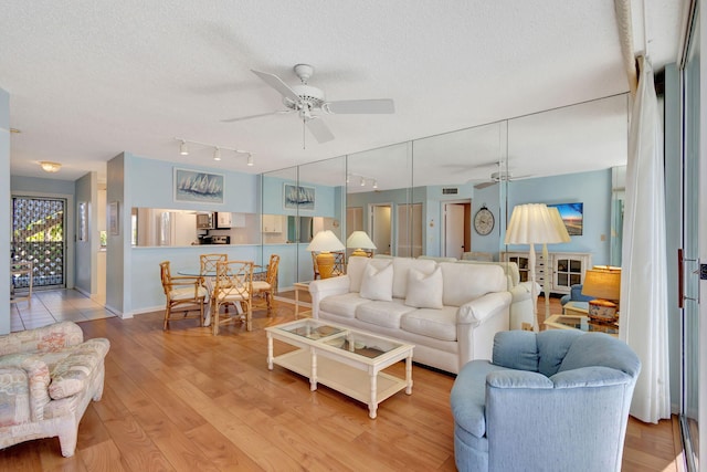 living room featuring ceiling fan, a textured ceiling, and light hardwood / wood-style flooring