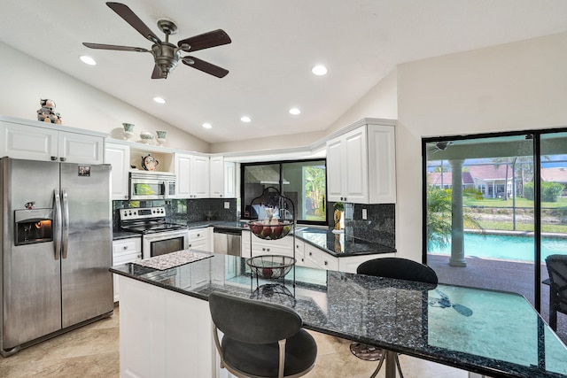 kitchen with a wealth of natural light, white cabinetry, lofted ceiling, a breakfast bar area, and appliances with stainless steel finishes