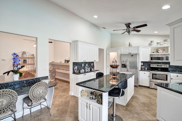 kitchen featuring white cabinetry, stainless steel appliances, dark stone counters, and tasteful backsplash