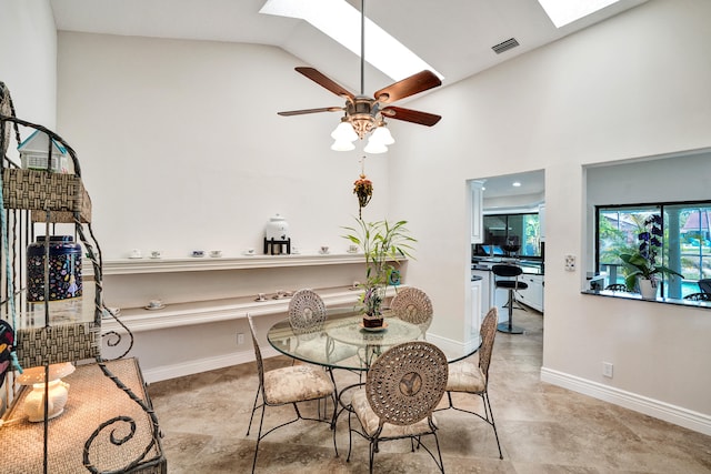 dining area featuring ceiling fan, high vaulted ceiling, and a skylight