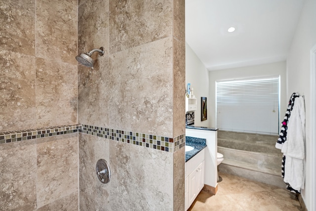 bathroom with a tile shower, vanity, and toilet